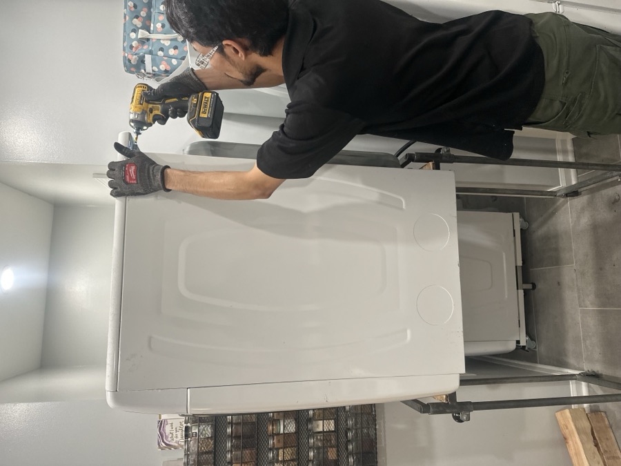 Technician installing a stacked laundry unit