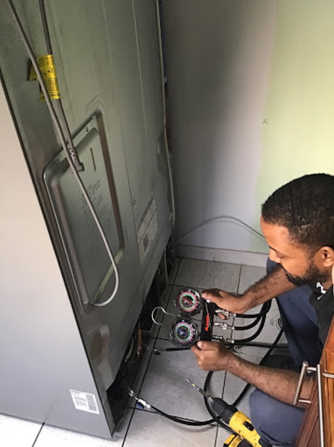 Technician testing a refrigerator's sealed system